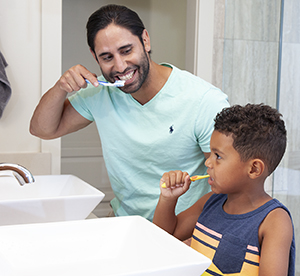 Man and boy brushing their teeth.