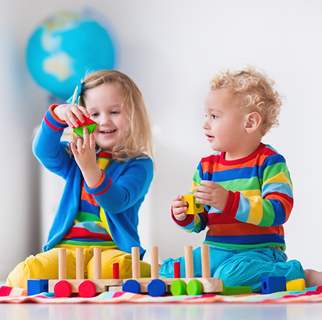 Two toddlers playing with blocks on the floor.